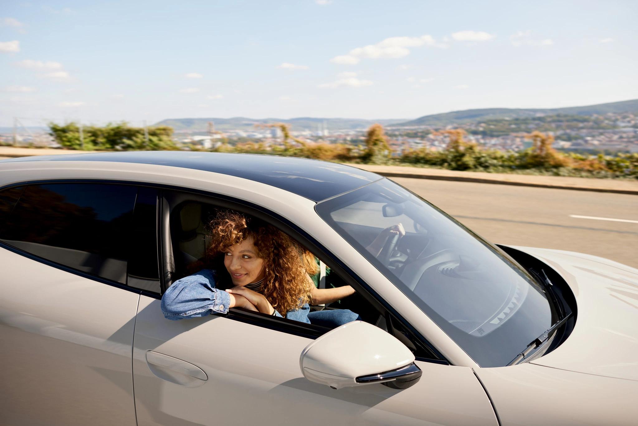 Eine Frau, die aus dem Fenster eines fahrenden Porsche sieht